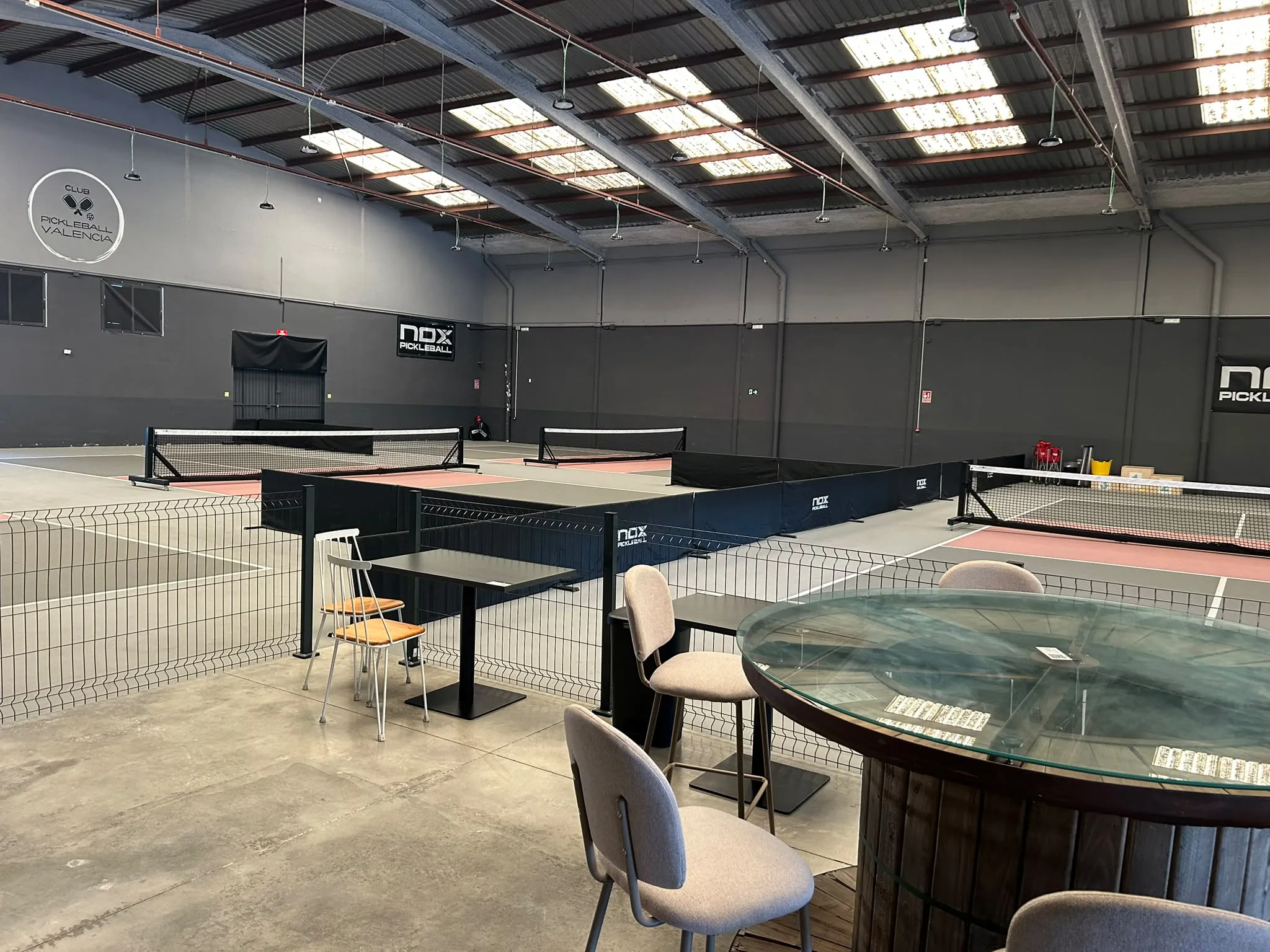 Pistas indoor del Club Pickleball Valencia con zona de mesas